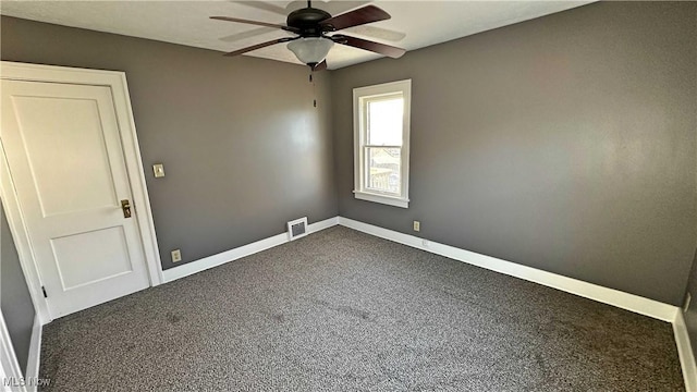 spare room featuring baseboards, visible vents, dark carpet, and ceiling fan