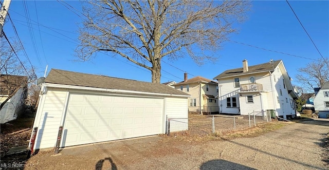 view of front of home featuring an outdoor structure, a balcony, fence, and a detached garage