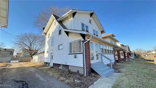 view of side of home featuring entry steps and fence