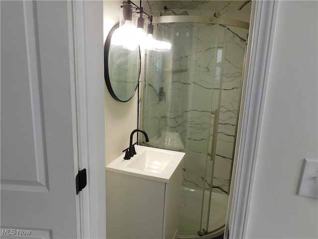 full bathroom featuring a marble finish shower and vanity