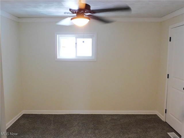 empty room featuring visible vents, dark carpet, baseboards, and a ceiling fan