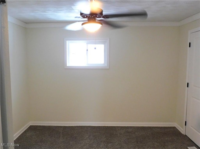 empty room featuring baseboards, ceiling fan, dark carpet, and ornamental molding