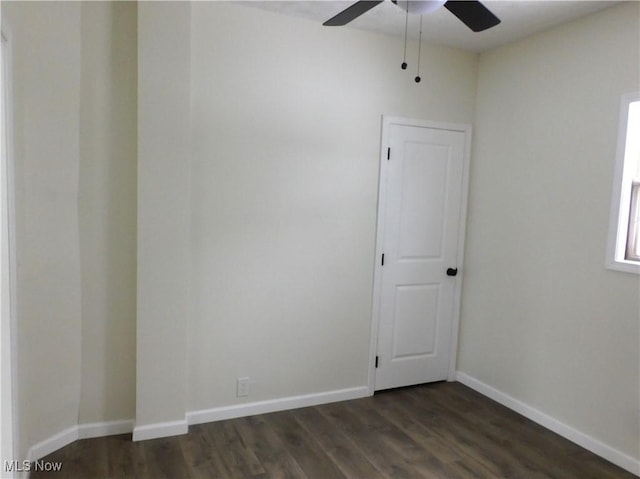 unfurnished room featuring a ceiling fan, dark wood-style flooring, and baseboards