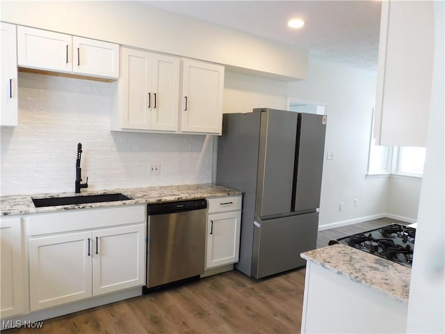 kitchen featuring a sink, decorative backsplash, appliances with stainless steel finishes, white cabinets, and dark wood-style flooring