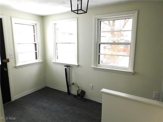 empty room with dark carpet and baseboards