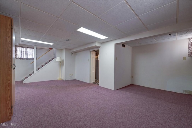 basement featuring stairs, carpet flooring, visible vents, and a drop ceiling