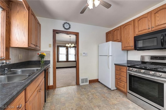 kitchen featuring visible vents, a sink, black appliances, dark countertops, and ceiling fan with notable chandelier