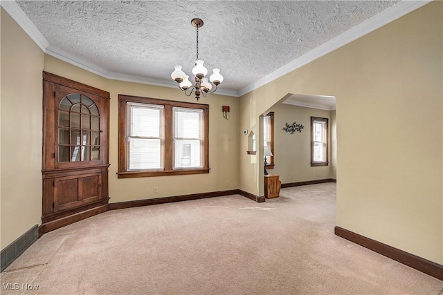 unfurnished room with baseboards, ornamental molding, light carpet, arched walkways, and a notable chandelier