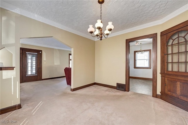 unfurnished room with visible vents, an inviting chandelier, crown molding, baseboards, and light colored carpet