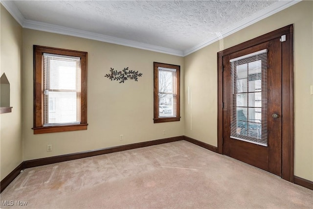 empty room featuring light carpet, a textured ceiling, baseboards, and ornamental molding