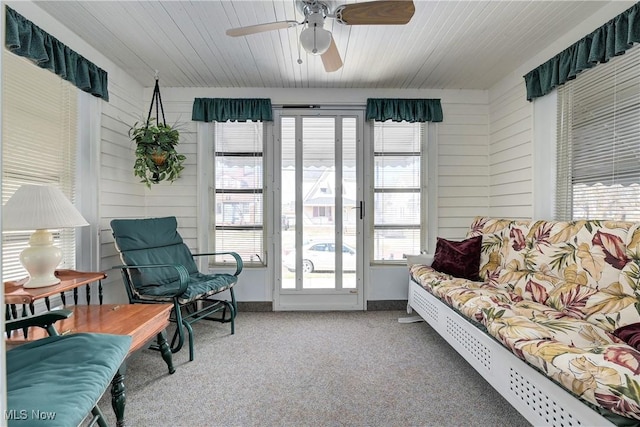 interior space featuring wooden walls, ceiling fan, and carpet floors