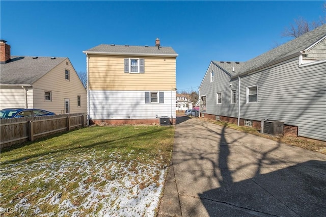 back of house with fence, a lawn, and central AC