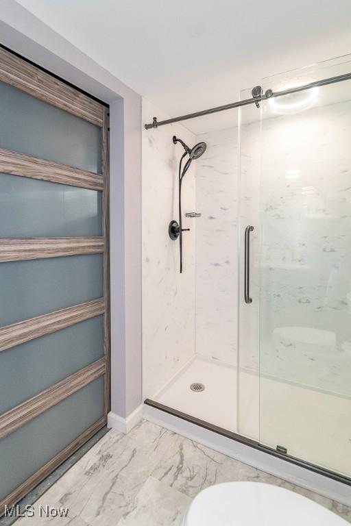 bathroom with a shower stall and marble finish floor