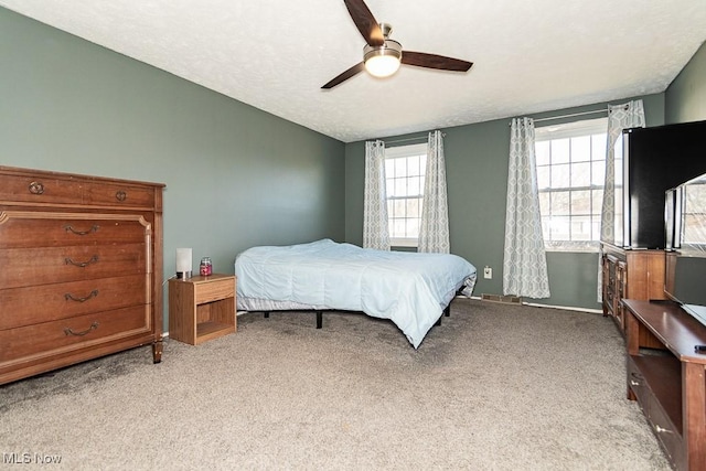 bedroom featuring light carpet, a textured ceiling, and ceiling fan