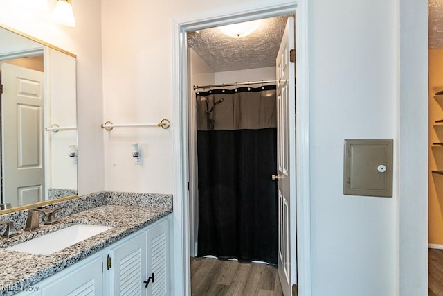 bathroom with vanity, a shower with shower curtain, wood finished floors, and a textured ceiling