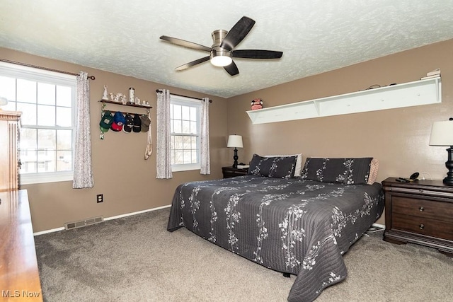 carpeted bedroom with a ceiling fan, baseboards, visible vents, and a textured ceiling