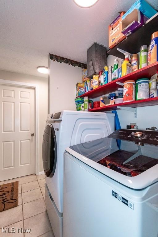 clothes washing area with laundry area, light tile patterned floors, and washing machine and clothes dryer