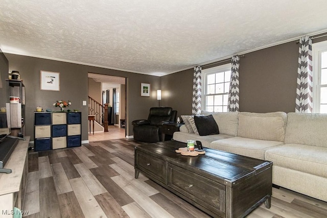 living area with baseboards, stairway, ornamental molding, wood finished floors, and a textured ceiling