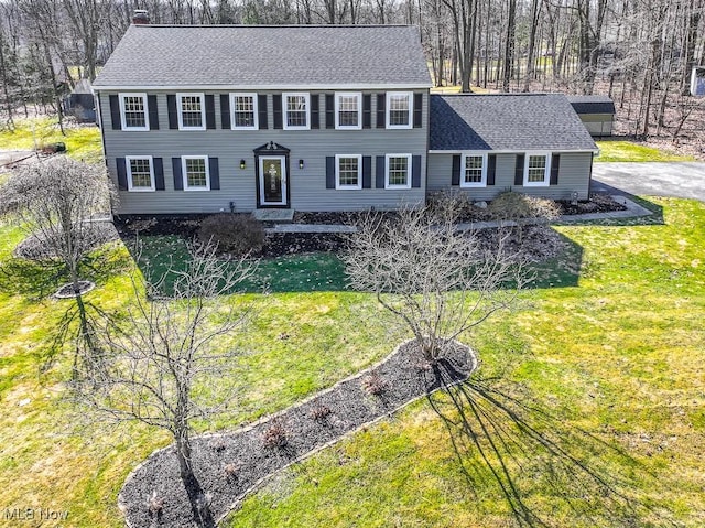 colonial house with roof with shingles and a front lawn