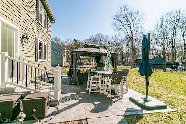 view of patio with a gazebo, outdoor dining space, and fence