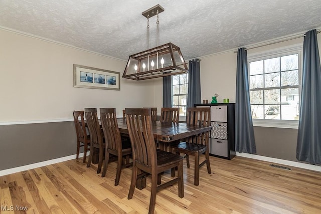 dining space featuring light wood-type flooring, visible vents, plenty of natural light, and an inviting chandelier