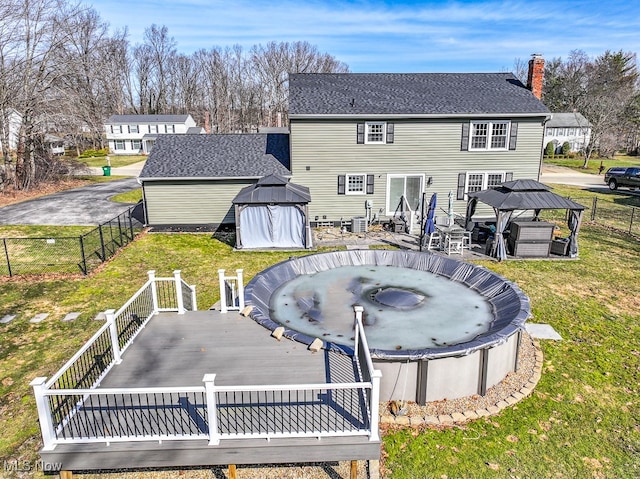 back of house with a gazebo, a lawn, a chimney, and a wooden deck