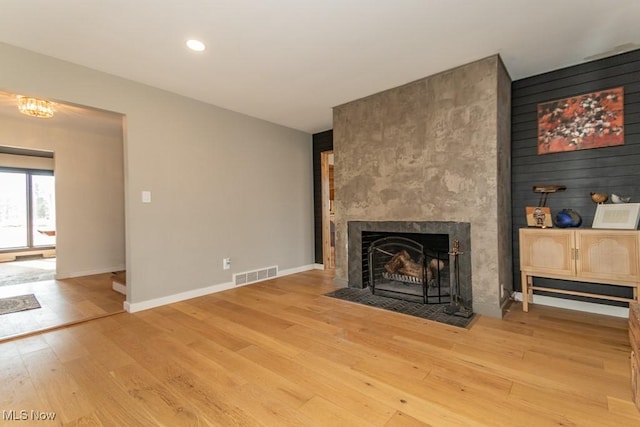 unfurnished living room featuring hardwood / wood-style flooring, a fireplace, visible vents, and baseboards