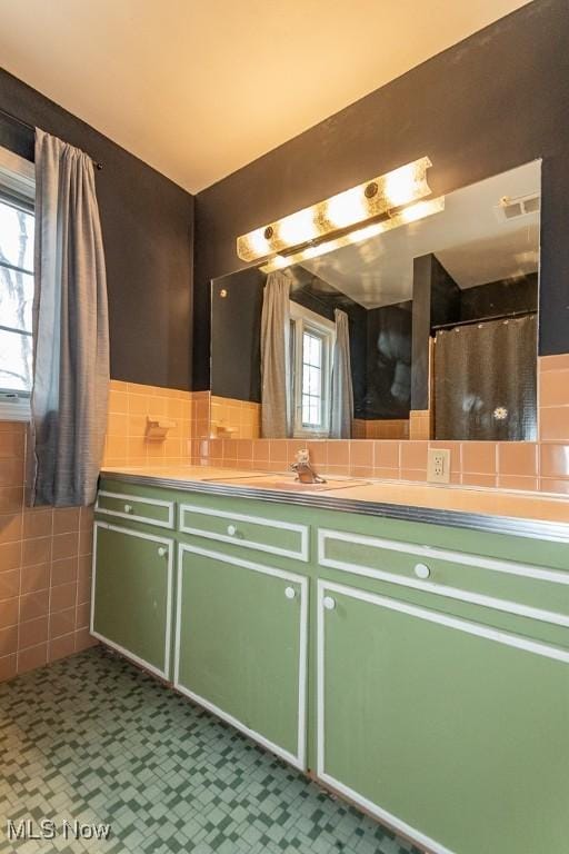 bathroom featuring visible vents, tile walls, and vanity