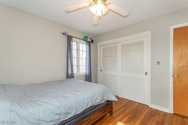 bedroom with a ceiling fan, wood finished floors, a closet, and baseboards