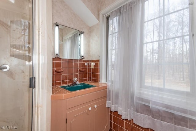 bathroom with tasteful backsplash, a stall shower, and vanity