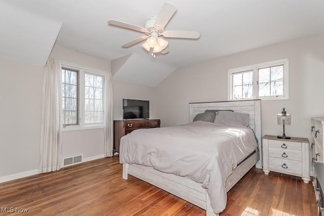 bedroom with visible vents, multiple windows, dark wood-style flooring, and vaulted ceiling