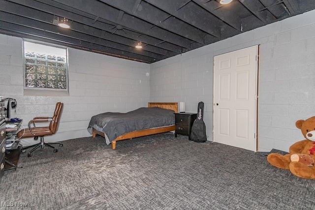 carpeted bedroom featuring concrete block wall