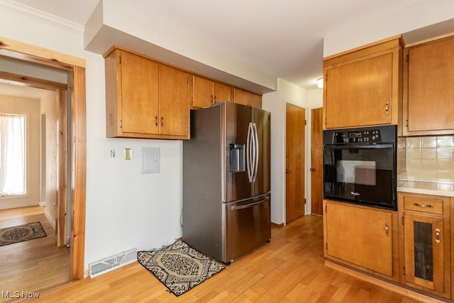 kitchen featuring oven, visible vents, brown cabinets, stainless steel refrigerator with ice dispenser, and light wood-style floors