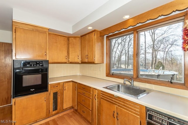 kitchen with a sink, light countertops, dishwasher, and oven