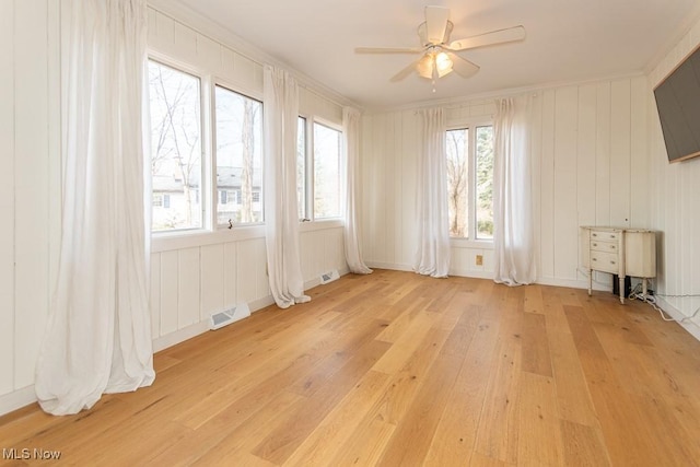 unfurnished room featuring crown molding, light wood-style flooring, a ceiling fan, and visible vents