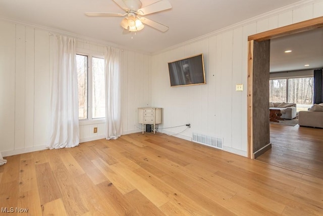 empty room with ceiling fan, crown molding, visible vents, and light wood-type flooring