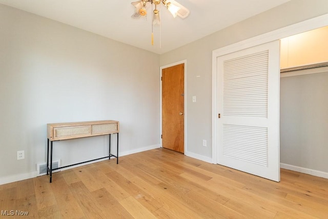 unfurnished bedroom with light wood-type flooring, visible vents, baseboards, and a closet