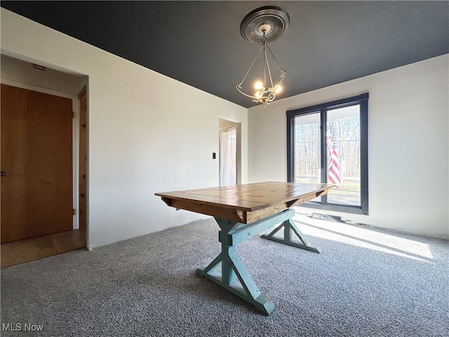 dining space with carpet flooring and a chandelier