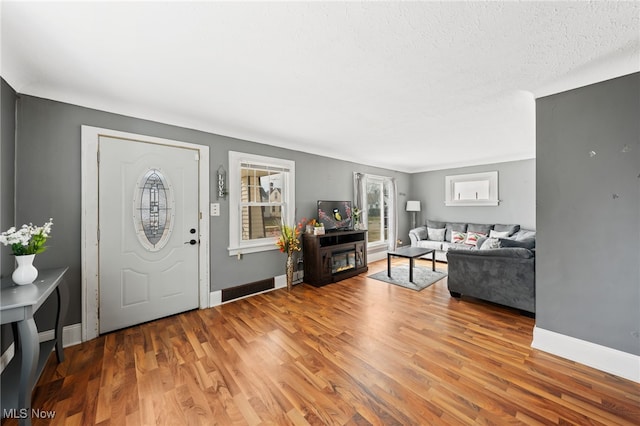 foyer featuring wood finished floors, baseboards, and a textured ceiling