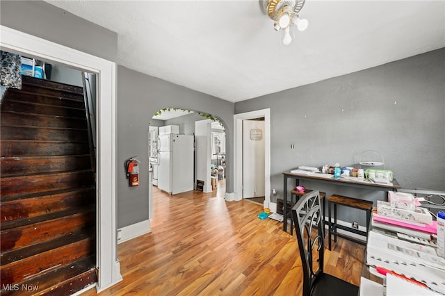 dining space featuring a ceiling fan, wood finished floors, arched walkways, baseboards, and stairs