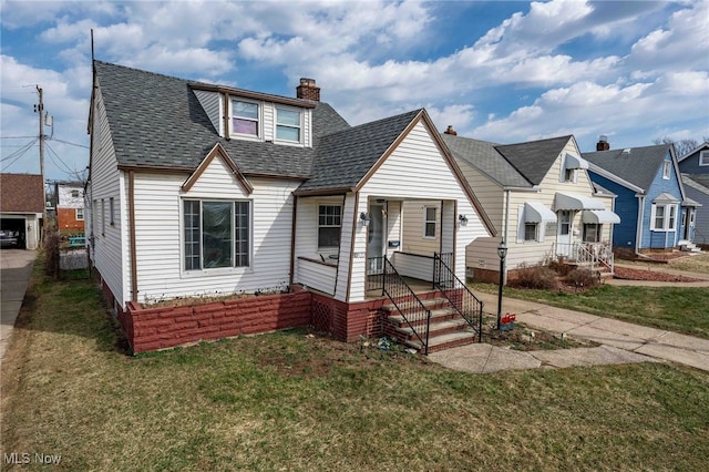 view of front of property with a chimney, a front lawn, and roof with shingles