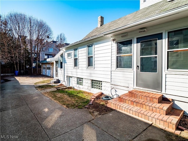 view of side of property with entry steps, driveway, and a chimney