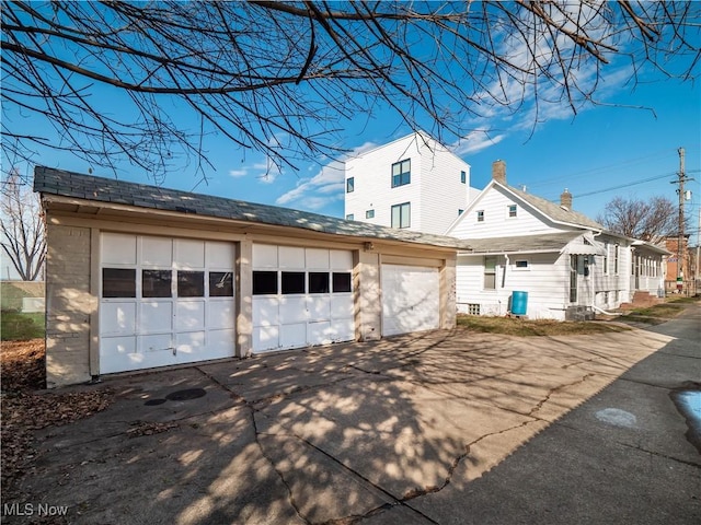 view of home's exterior featuring an outdoor structure, a garage, and roof with shingles