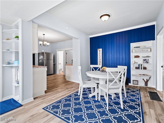 dining area with visible vents, baseboards, a notable chandelier, and light wood-style flooring