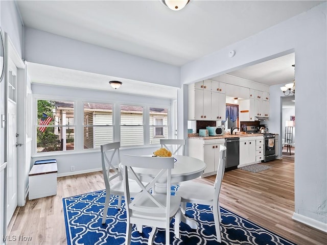 dining room featuring light wood-style flooring, an inviting chandelier, and baseboards