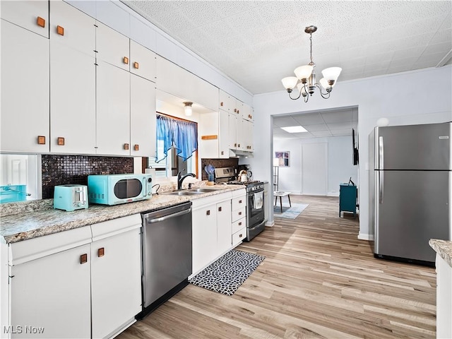 kitchen featuring light wood-style flooring, a notable chandelier, white cabinets, stainless steel appliances, and a sink