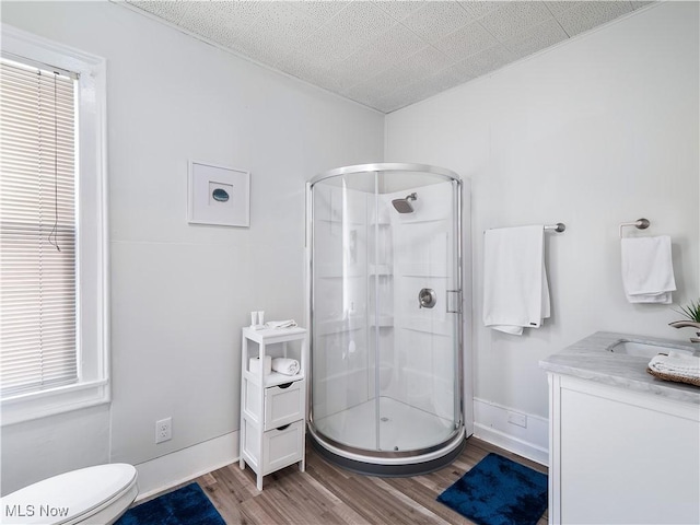 full bath with vanity, toilet, wood finished floors, and a stall shower