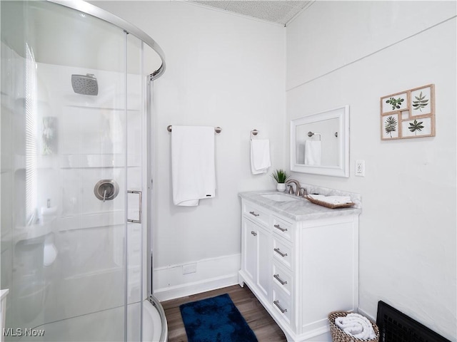 full bathroom featuring vanity, wood finished floors, a stall shower, and baseboards