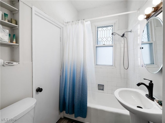 bathroom with toilet, shower / bath combo with shower curtain, and a sink