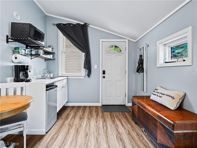 kitchen featuring a sink, white cabinetry, black microwave, light wood finished floors, and lofted ceiling